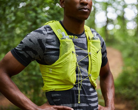 trail runner standing in the forest wearing the Salomon Advanced Skin Set Pack in sulphur spring yellow